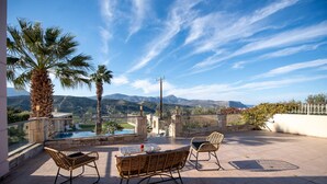 A terrace with wicker furniture, a pool, and a mountain view. - Villa Angels in Crete (Malevizi)