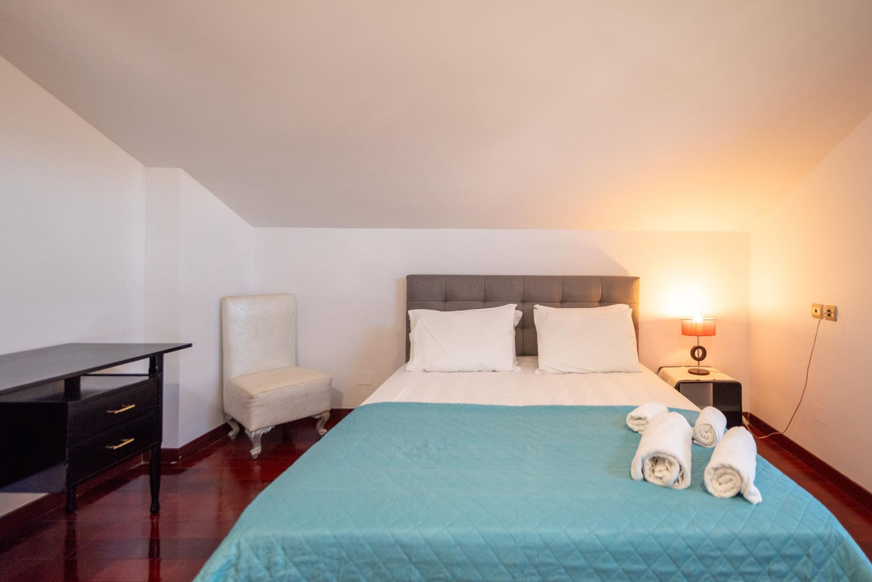 A neatly arranged hotel room with a bed, a desk, and a chair.