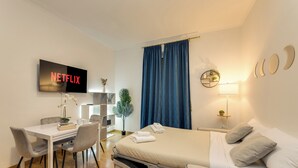 A modern hotel room with a bed, a desk, and a television displaying the Netflix logo. - Colosseum Sweet Life Apartment  (Rome)