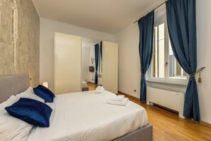 Un dormitorio con cama, espejo, ventana con cortinas y radiador.
