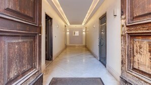 A hallway with wooden doors and a tiled floor. - Colosseum Sweet Life Apartment  (Rome)