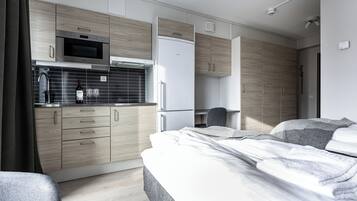 Un dormitorio moderno y compacto con cama, mesitas de noche y una pequeña zona de escritorio.