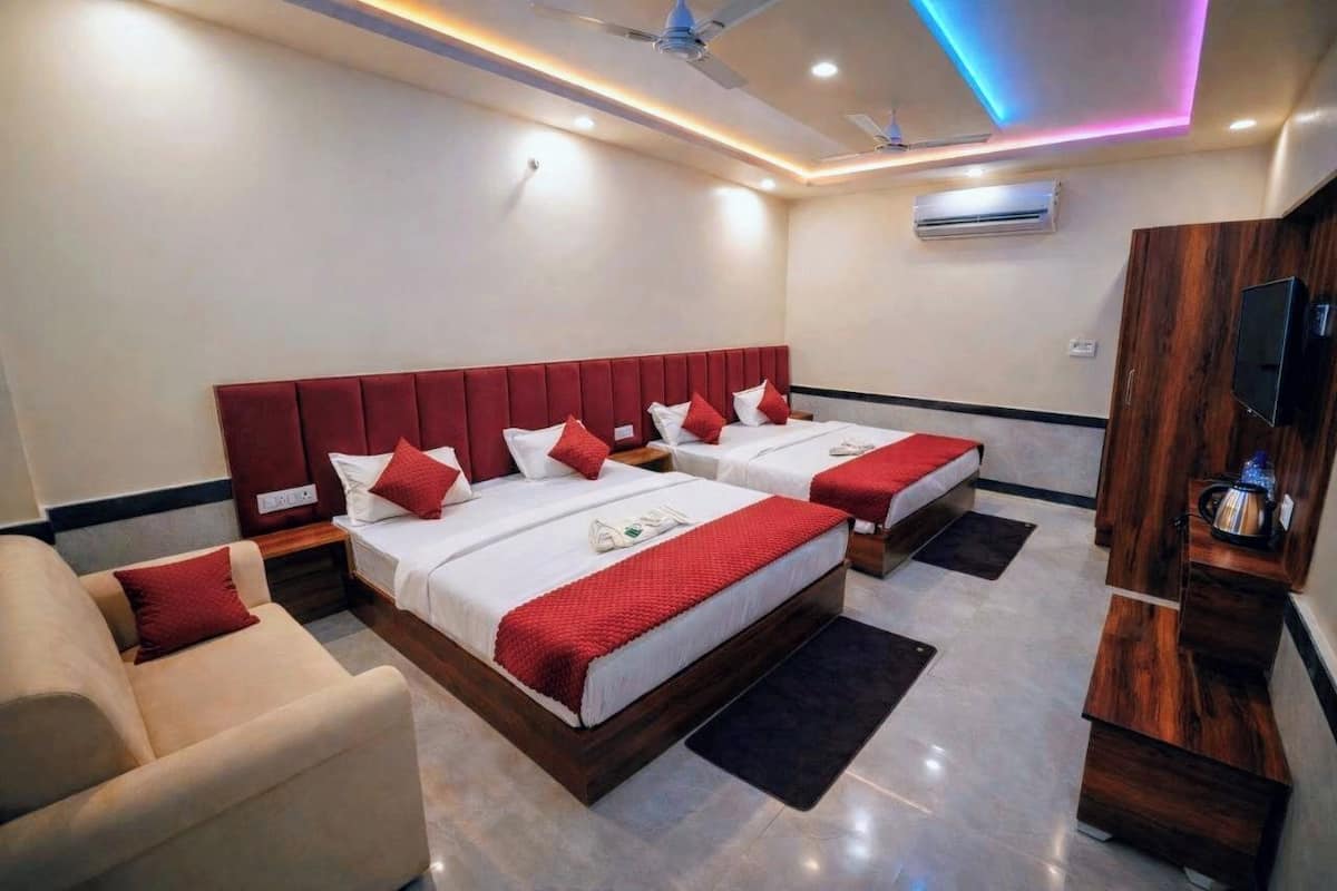 A hotel room with two beds, a TV, and a ceiling fan.