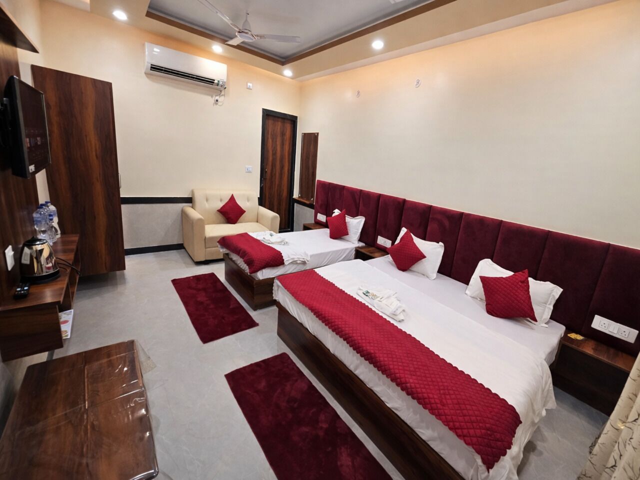A hotel room with two beds, a sofa, a wooden desk, and a TV.