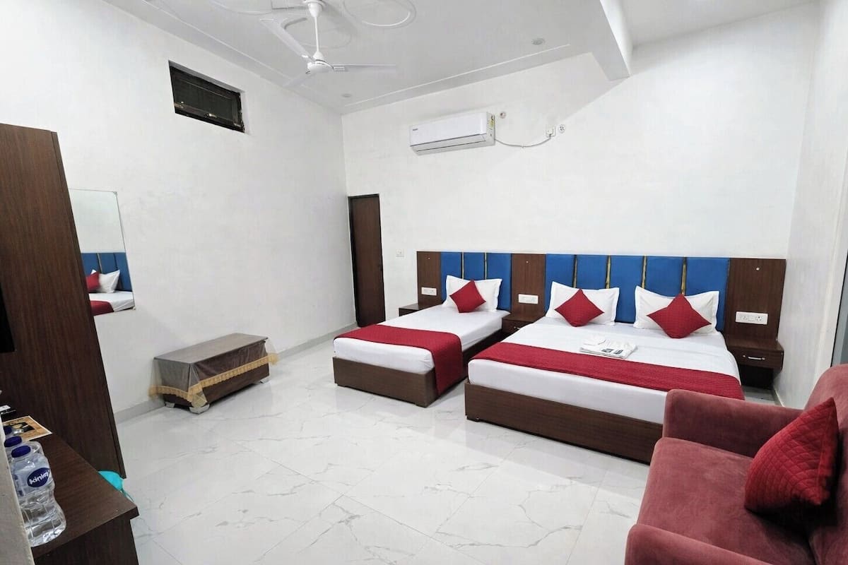 A hotel room with two beds, a desk, a chair, and a minibar.