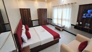 Habitación de hotel con cama, sofá, televisor y ventilador de techo.