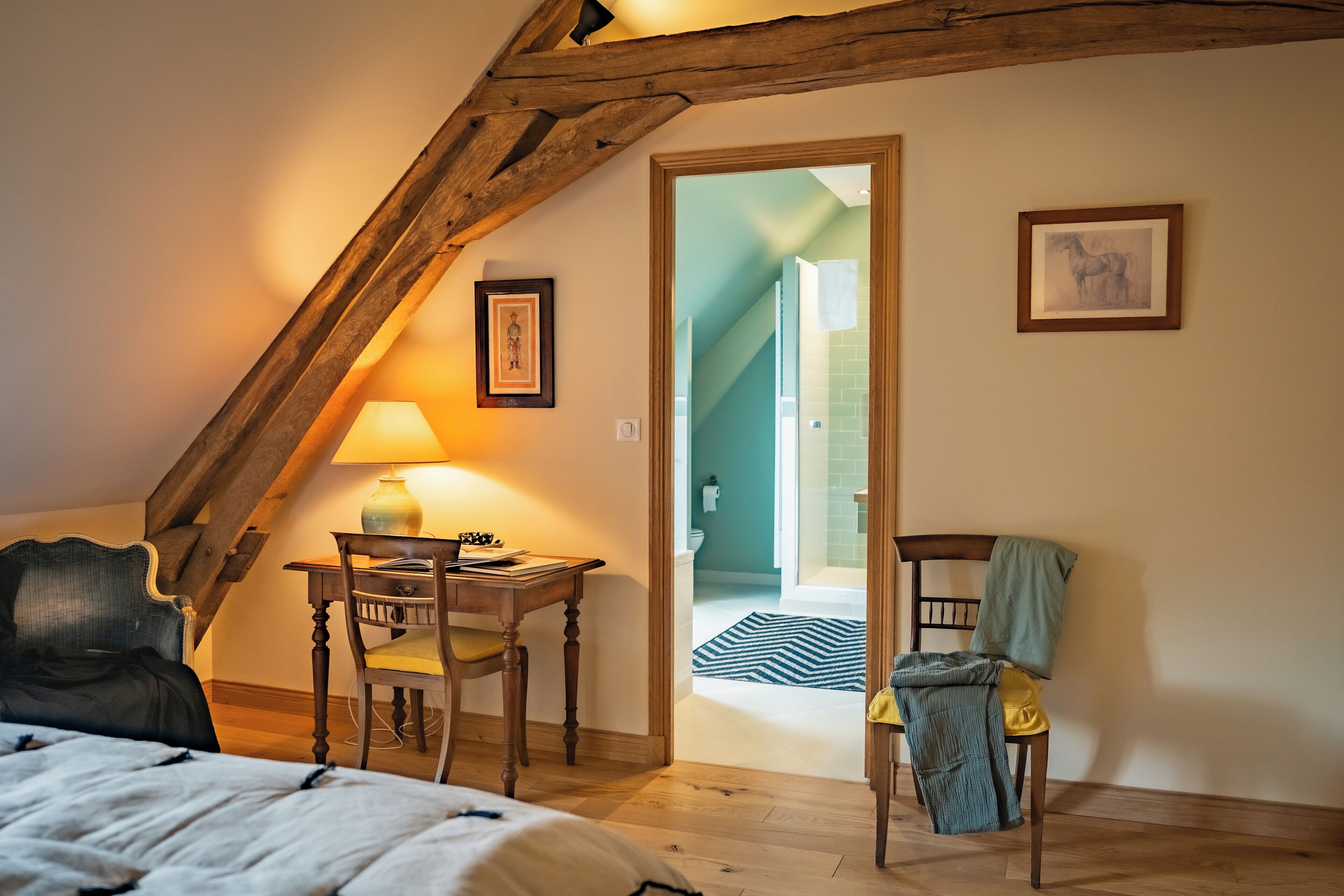 Un dormitorio con cama, escritorio y silla. Hay una puerta que da a otra habitación.