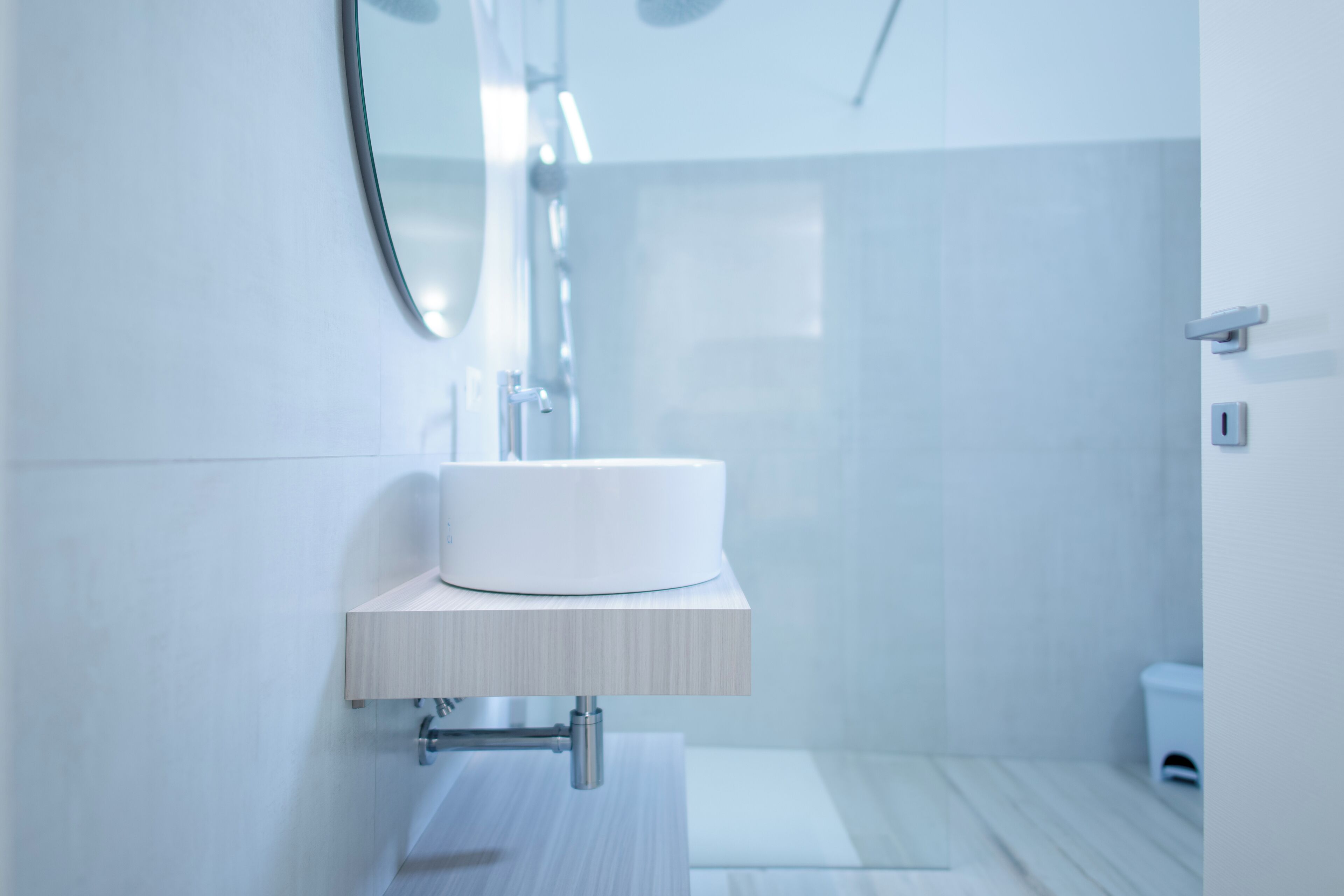 Ein modernes Badezimmer mit Waschbecken, Holzauskładung und einer Duschkabine aus Glas.