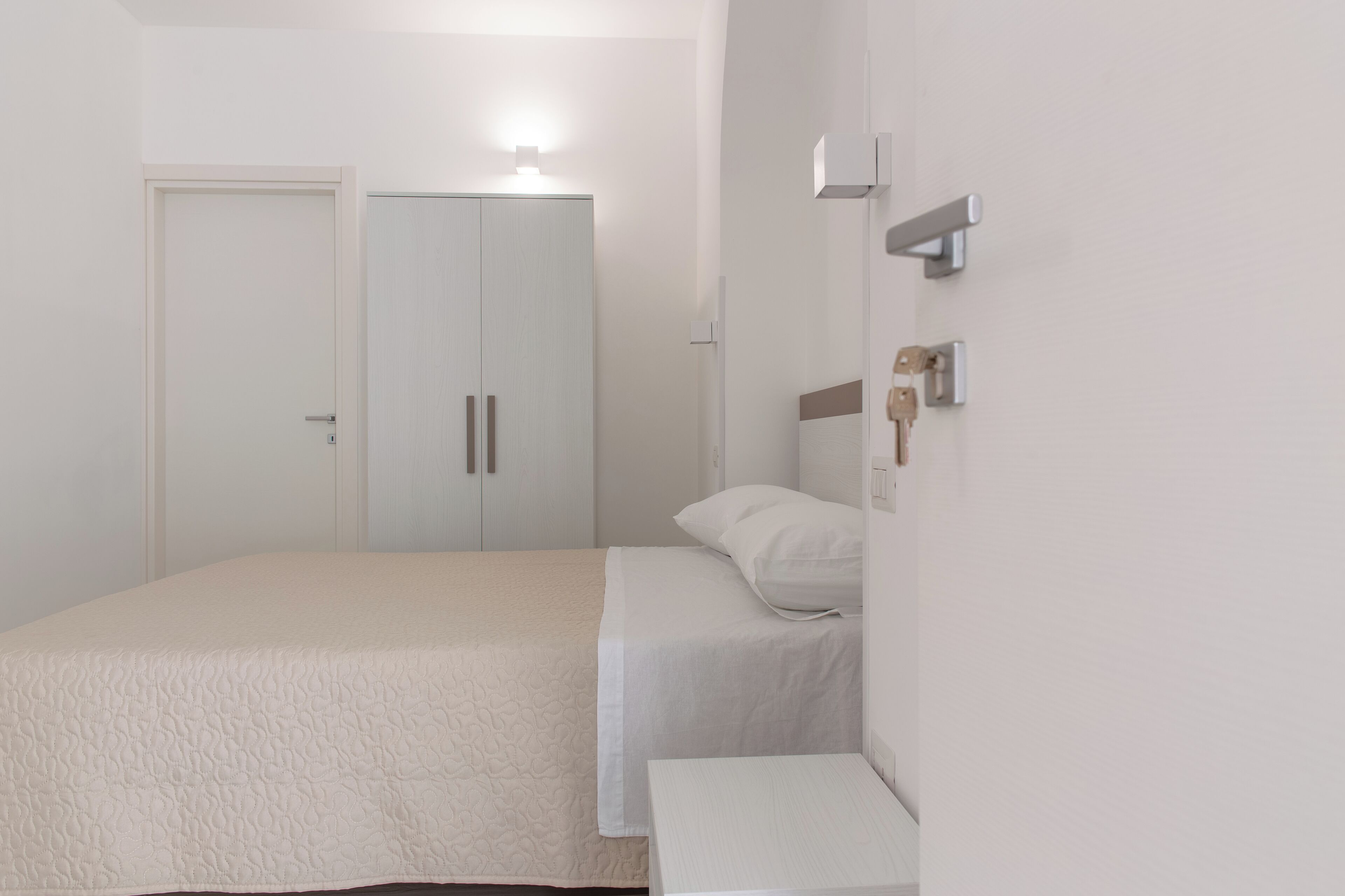 A minimalist bedroom with a bed, bedside table, and a wardrobe.
