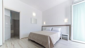Un dormitorio moderno con una cama grande, una mesita de noche y una puerta corrediza de vidrio que da a un balcón.