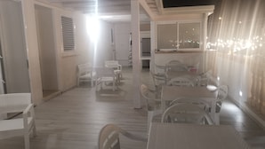 Un espacio interior amplio con diversas opciones de mobiliario, incluyendo mesas y sillas, y vistas al exterior a través de amplias ventanas.