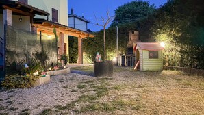 Une propriété résidentielle dotée d’une allée pavée, d’une petite maison de jeu et d’un jardin agrémenté de plantes et d’un champignon décoratif.