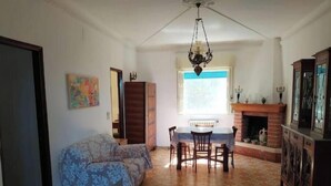 A living room with a sofa, dining table, chairs, a fireplace, and a patterned floor. - The house in the woods (Gorgofreddo)