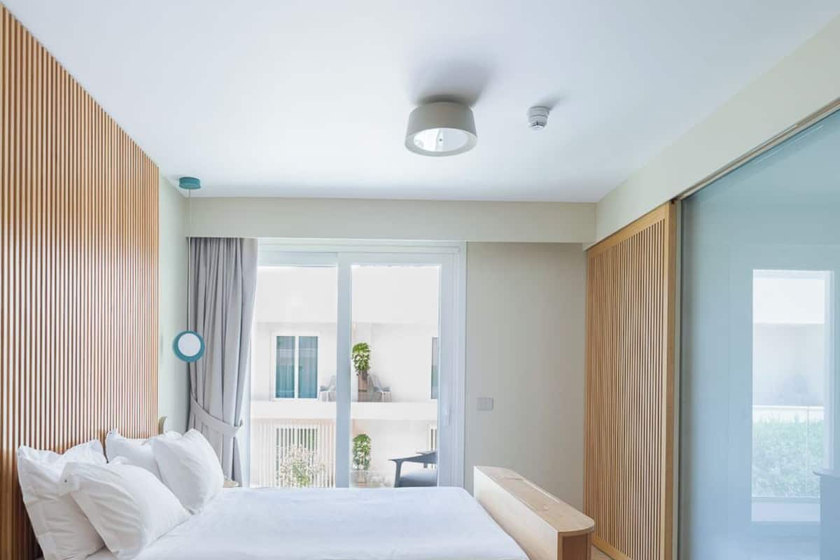 Quarto moderno com cama grande, escrivaninha e vista para o exterior.