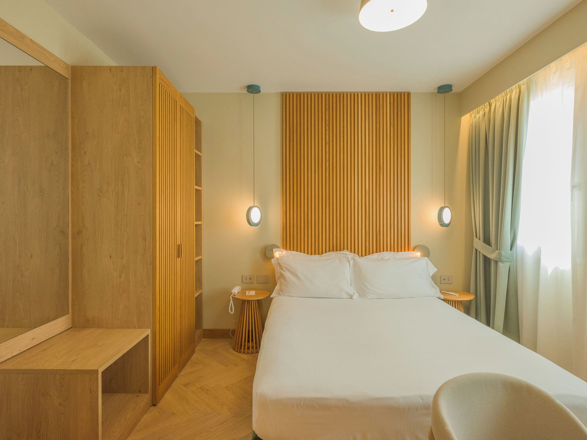 Una habitación de hotel con cama, mesitas de noche, armario y zona de estar.