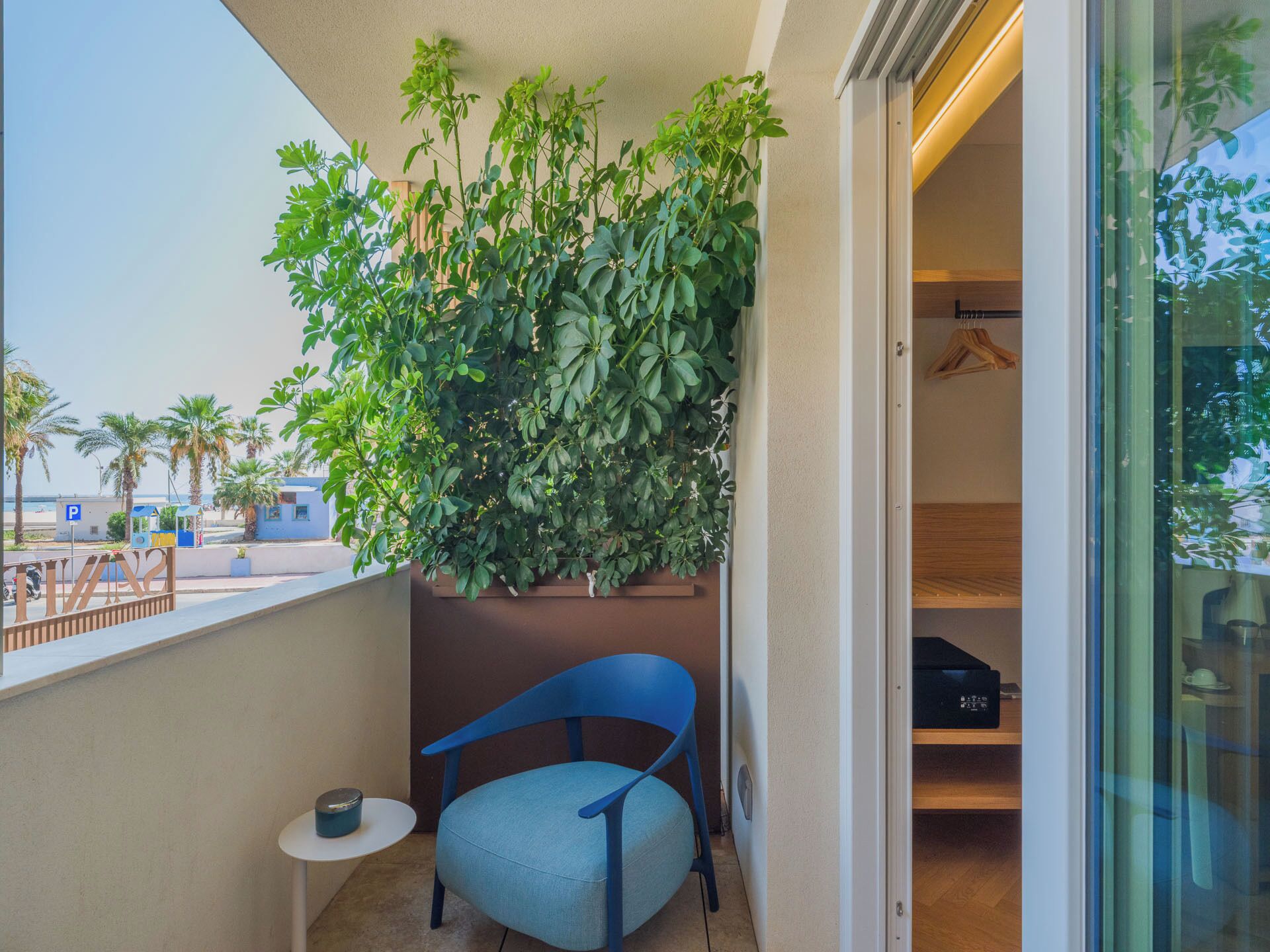 Ein Balkon mit einem Blumentopf, einem blauen Stuhl und einem kleinen Tisch.