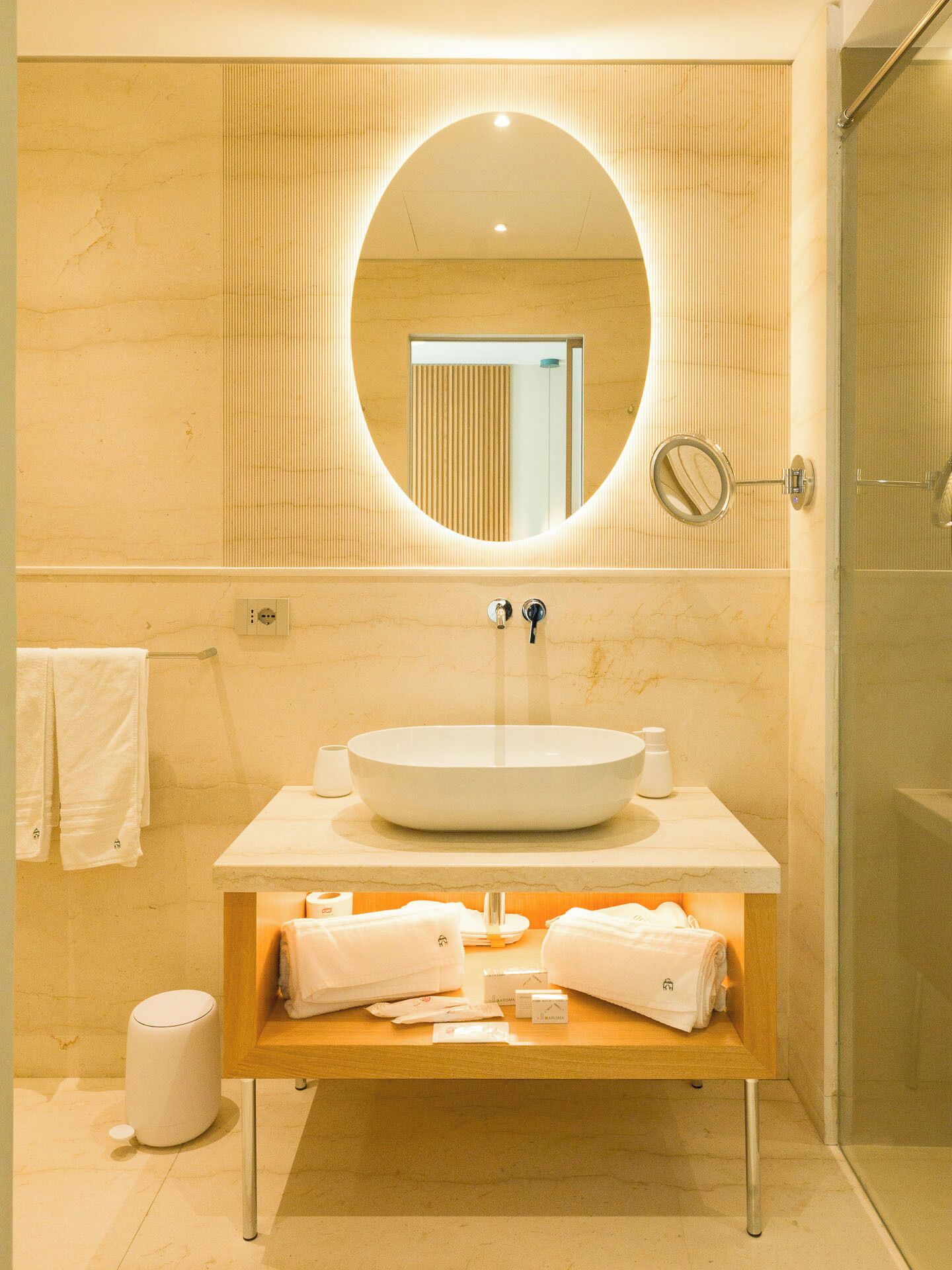 Ein Badezimmer mit einem runden Spiegel, einem Waschbecken und einer Holz-Waschkommode.