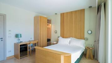 Quarto de hotel com cama, escrivaninha, cadeira, guarda-roupa e uma pequena mesa redonda.