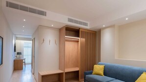 Una sala de estar moderna con un sofá azul, estanterías de madera y un vestidor.