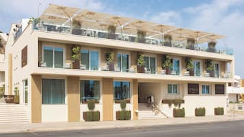Un hotel moderno con tejado plano, varios balcones y zonas de estar al aire libre.