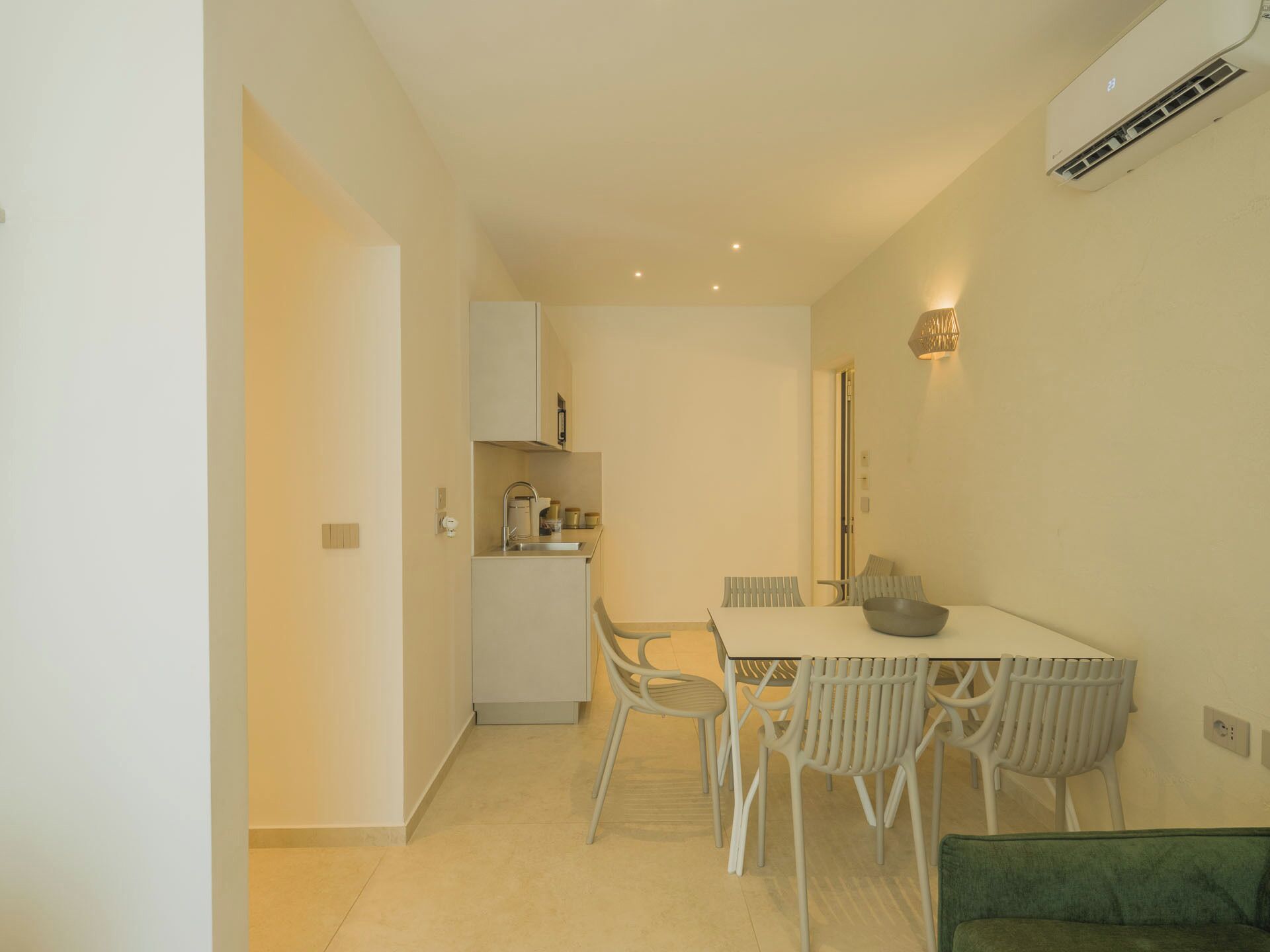 A compact kitchen with a dining area, including a table with chairs and a green sofa.