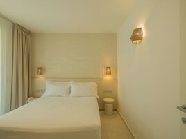 Una habitación de hotel con una cama grande, dos lámparas de noche, un teléfono en la mesita de noche y una pequeña mesita de noche.