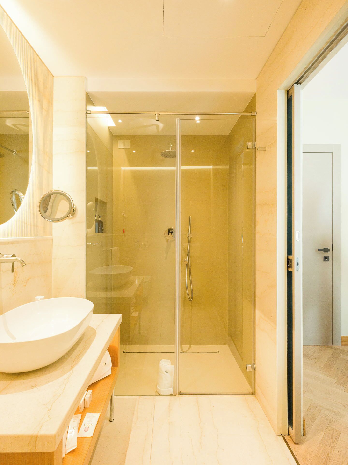 Ein modernes Badezimmer mit einer gläsernen Duschkabine, einem großen Waschbecken und einem Spiegel.
