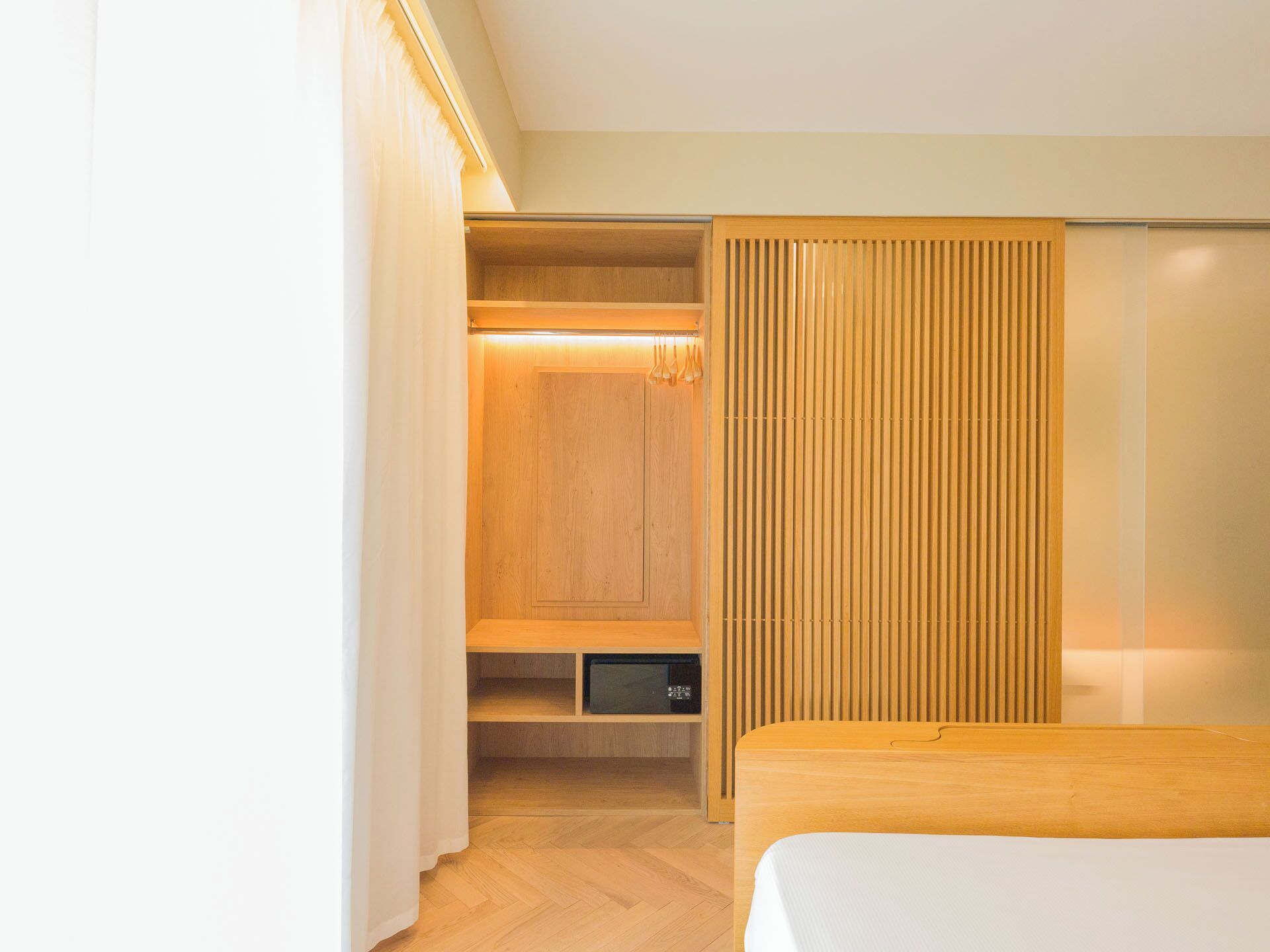A modern bedroom with a wooden bed, a built-in wardrobe, and a bedside table.