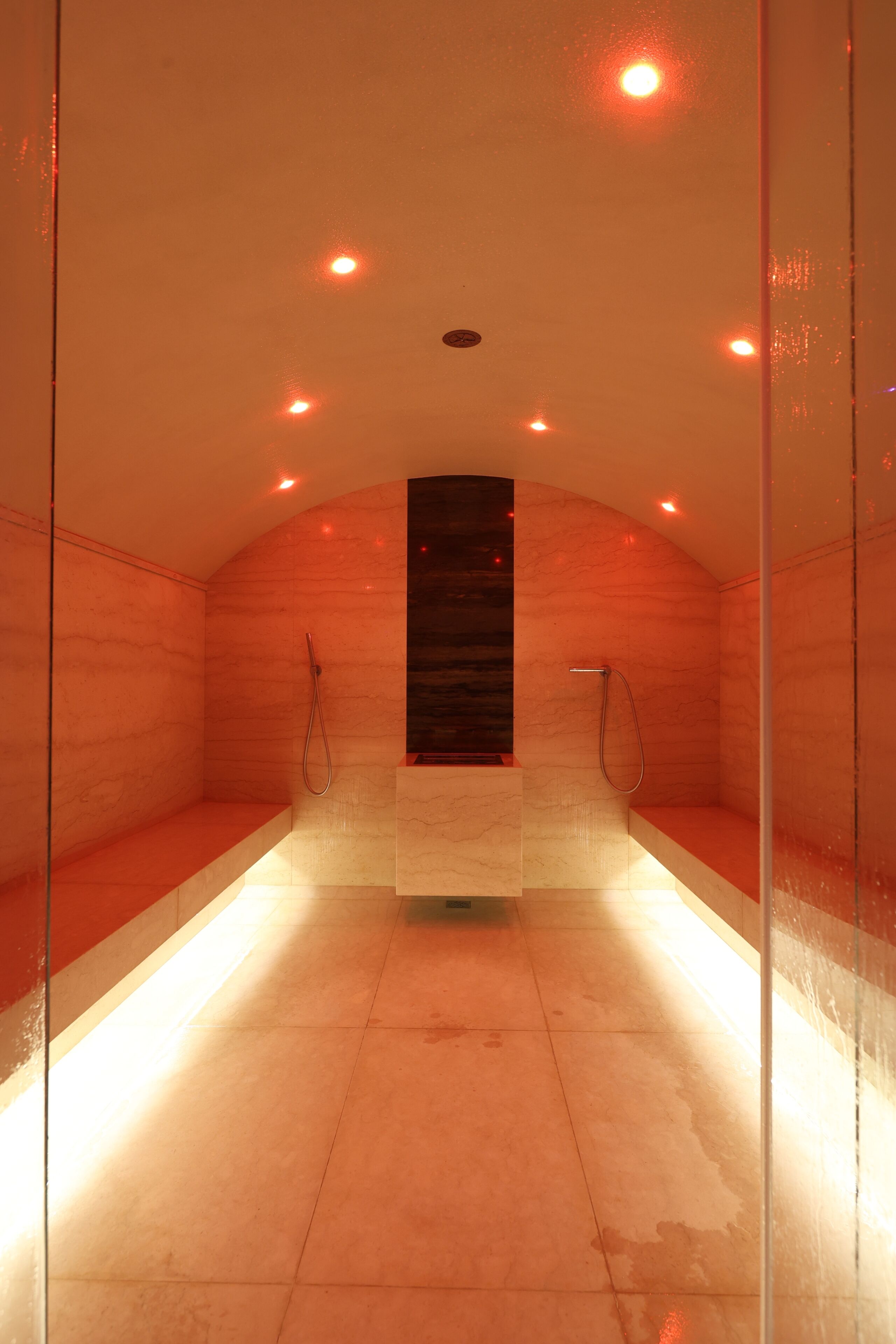Eine Sauna mit Glastrennwand, einer Holzbank und einer zentralen Säule.