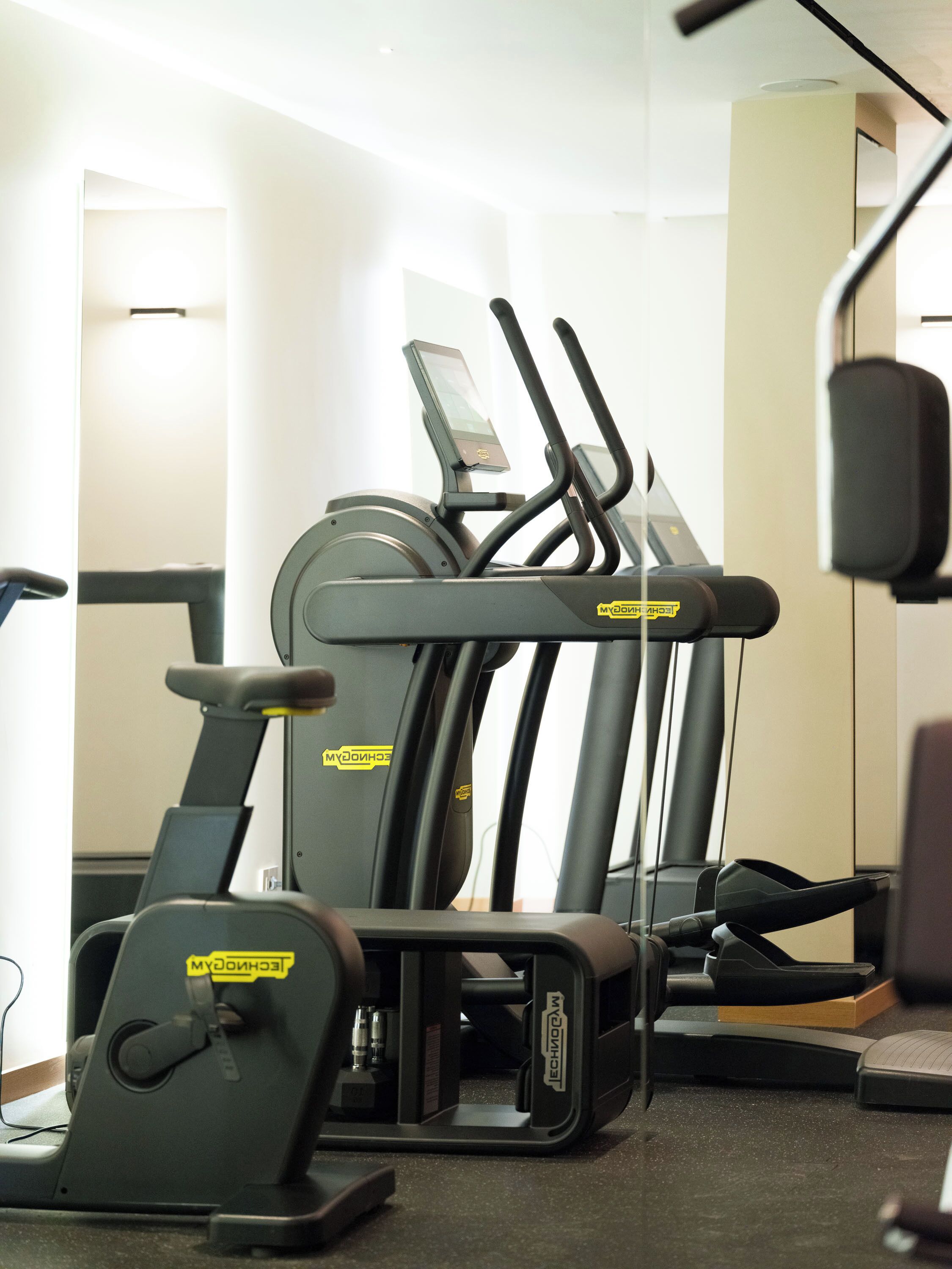 Een sportschool met trainingsapparatuur, waaronder loopbanden en een elliptische machine.