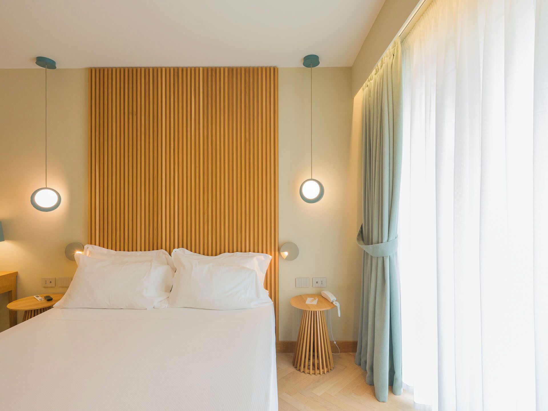 Ein Hotelzimmer mit einem Bett, Nachttischen, einer Wandleuchte und einem Vorhang.