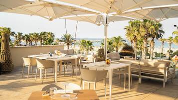 Una terraza con mesas al aire libre, una mesa de comedor y sombrillas.