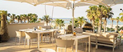 A terrace with outdoor seating, a dining table, and umbrellas.