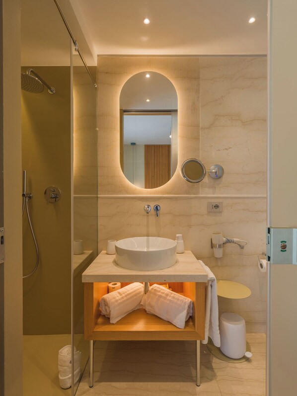 A modern bathroom with a large oval sink, a handheld showerhead, a mirror, and a towel rack. - San Vito Resort & Spa (San Vito Lo Capo)