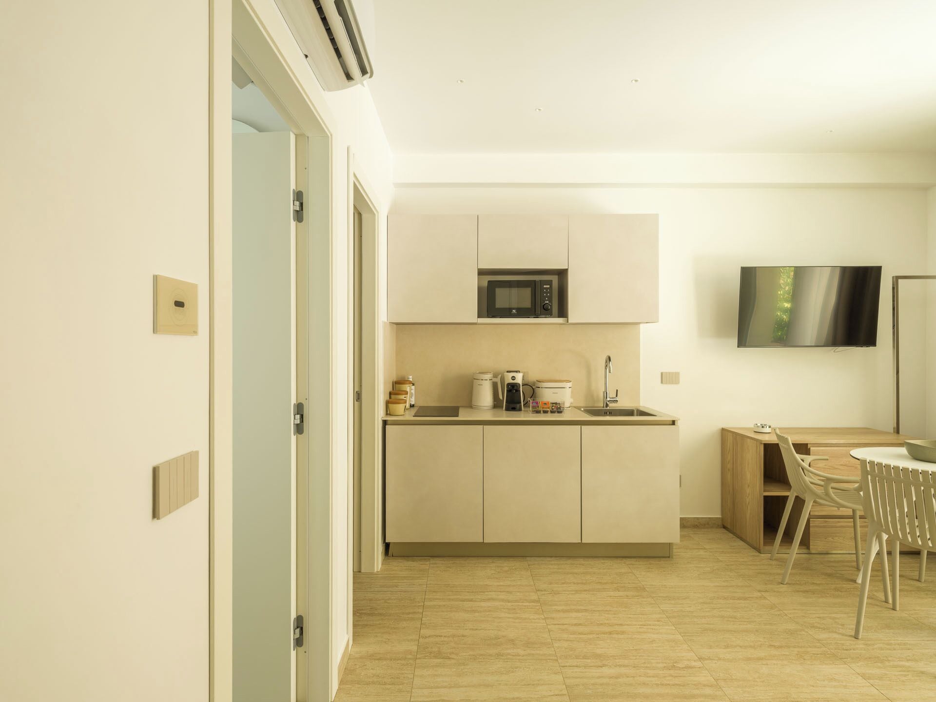 Cocina moderna con microondas, cafetera y lavabo. Cuenta con un comedor con mesa y sillas.