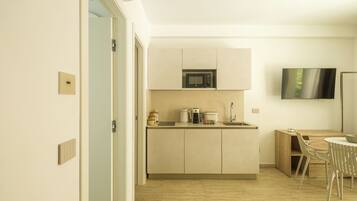 Cocina moderna con microondas, cafetera y lavabo. Cuenta con un comedor con mesa y sillas.