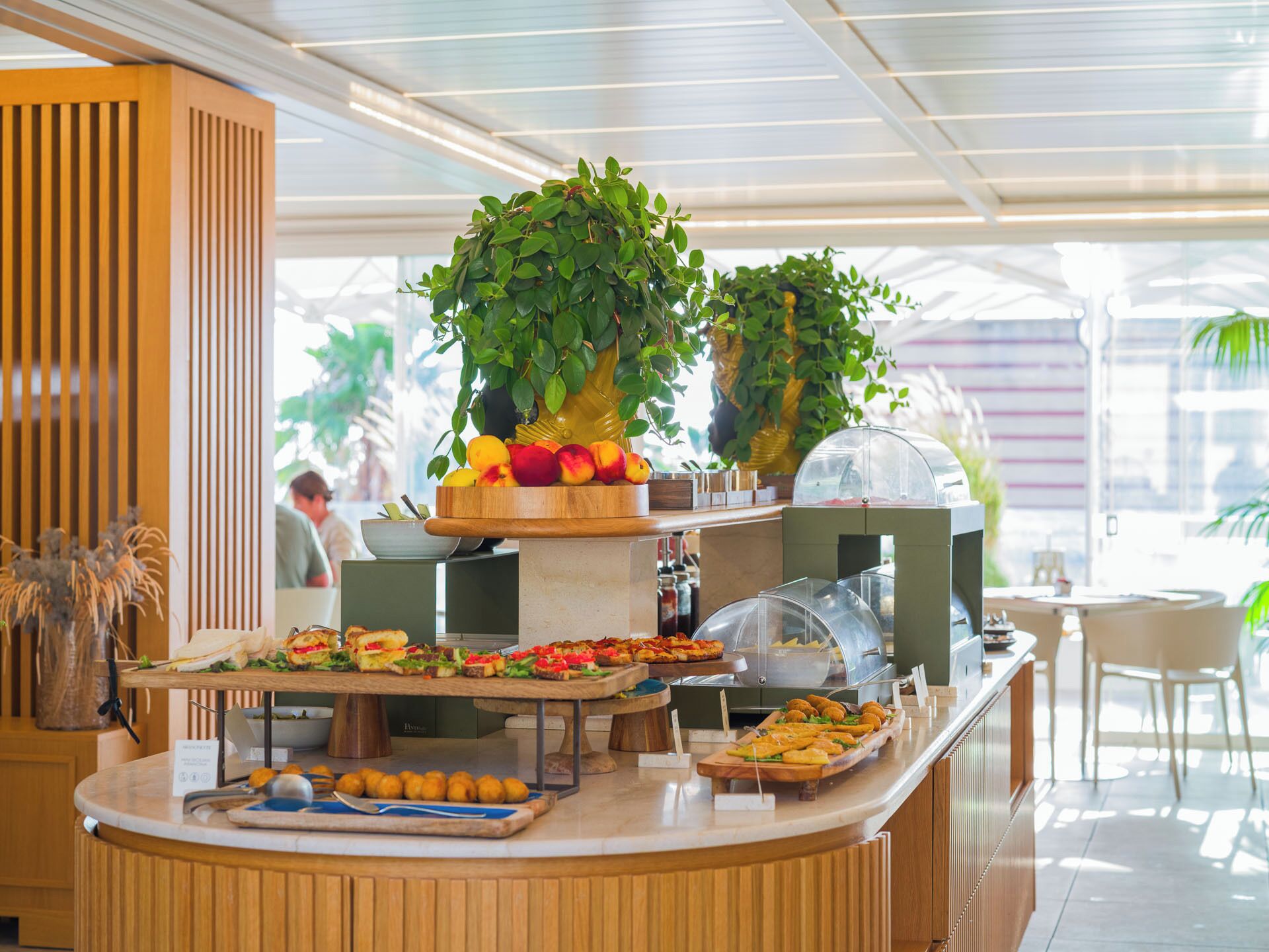 A buffet setup with various food items, a fruit display, and a seating area.