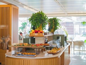 A buffet setup with various food items, a fruit display, and a seating area. - San Vito Resort & Spa (San Vito Lo Capo)