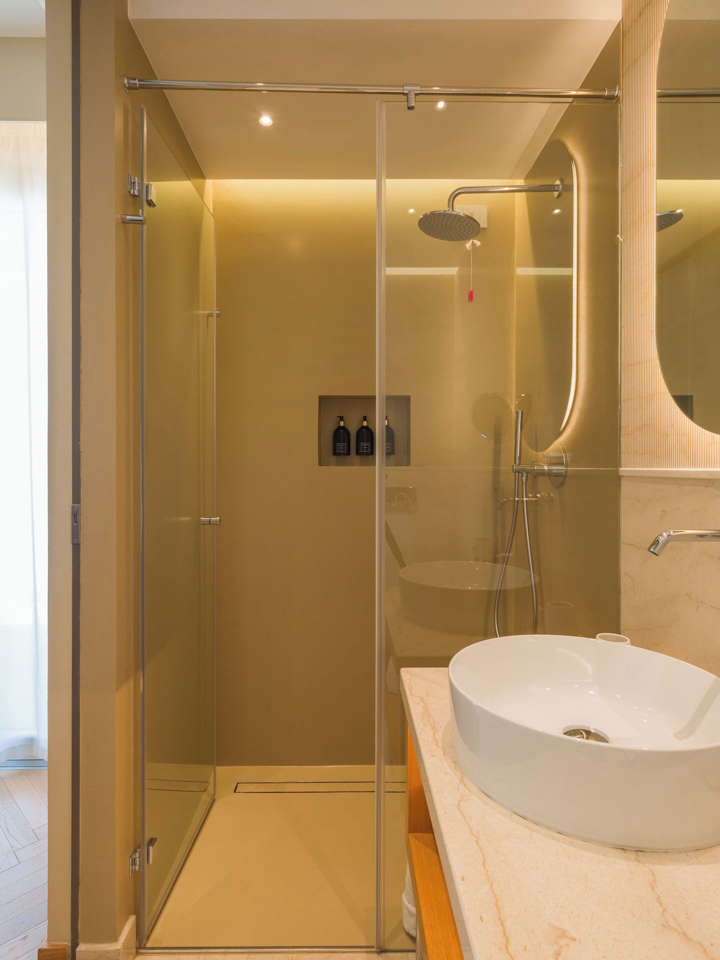 A modern bathroom with a glass-enclosed shower, a white sink, and a marble countertop.