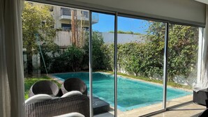 Une chambre moderne dotée d’une grande porte-fenêtre coulissante donnant accès à un espace piscine privé.
