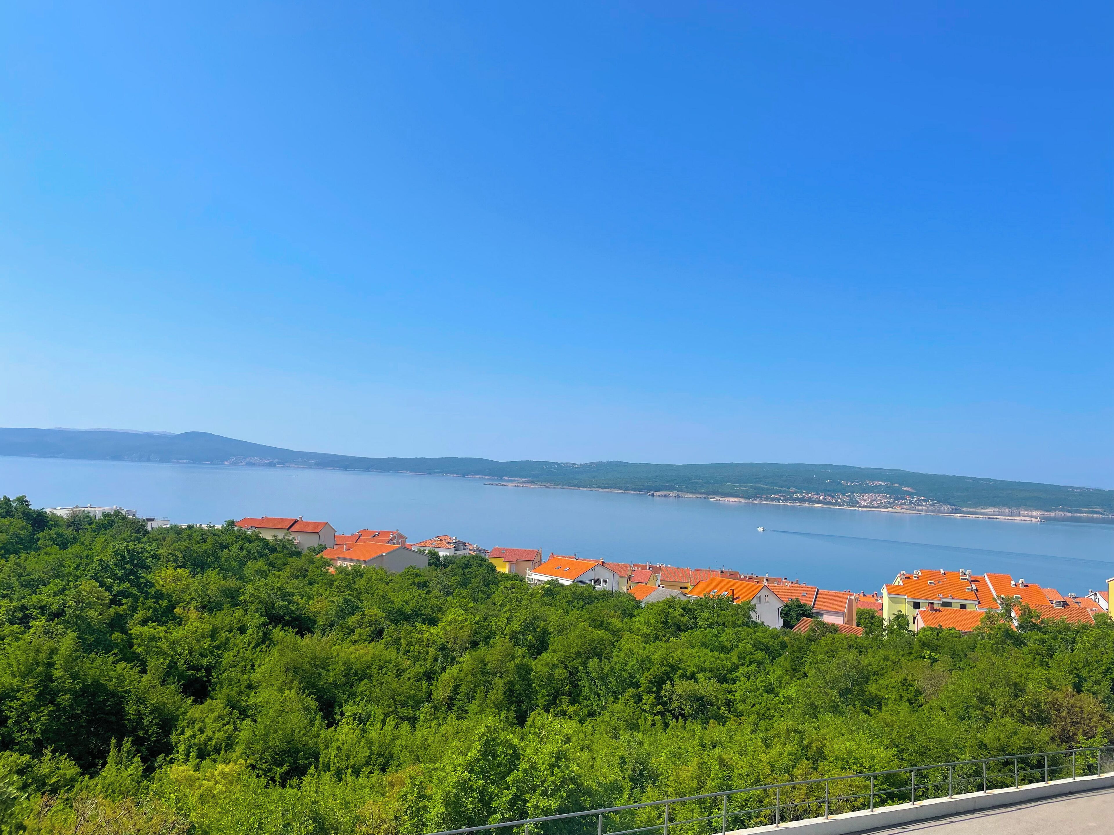 Eine Küstenstadt mit roten Dächern, wolkenlosem, blauem Himmel und Blick auf das Meer.