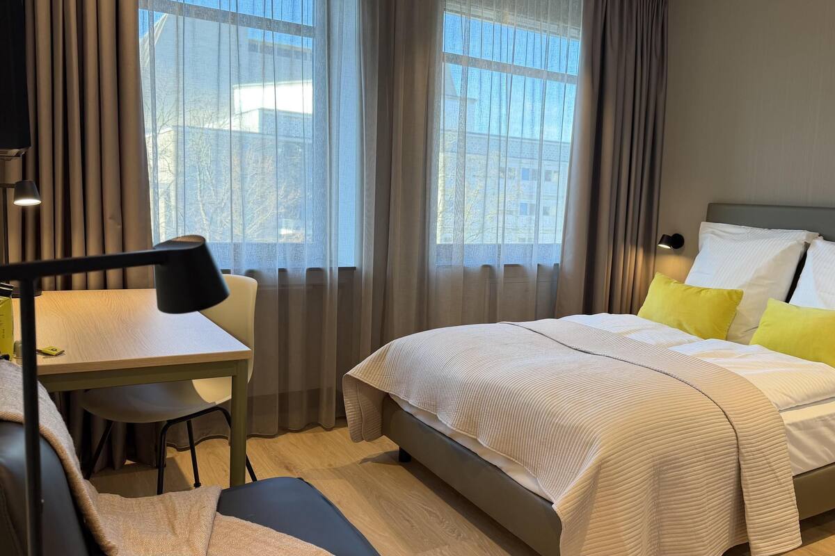 Une chambre d’hôtel avec un lit, un bureau, une chaise et une lampe.