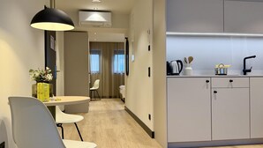 A modern hotel room with a dining area, a kitchenette, and a hallway leading to a bedroom. - ipartment Koeln Oper @HOME by Best Western (Cologne)