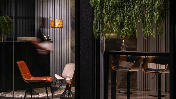 A modern interior with a seating area featuring two chairs, a table, and a hanging plant. - BRYQs Hotel Kuala Lumpur (Kuala Lumpur)