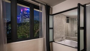 A modern bathroom with a large window, a bathtub, and a cityscape view. - BRYQs Hotel Kuala Lumpur (Kuala Lumpur)