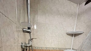 Área de chuveiro com chuveiro manual e torneira fixada na parede.
