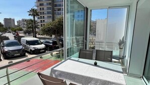 A balcony with a table and chairs, overlooking a parking area with several cars and buildings in the background. - Lovely studio apartment next to the beach AV-63 (ROSES)