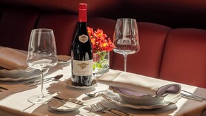 A dining table set with wine glasses, a bottle of wine, and a vase of flowers. - HOTEL BOUTIQUE FARO SILLEIRO (Baiona)