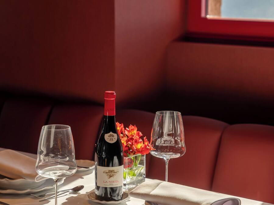 A dining table set with wine glasses, a bottle of wine, and a vase of flowers.