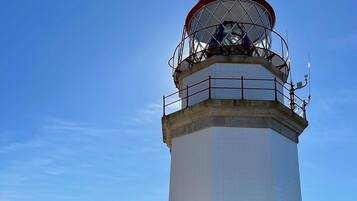 A lighthouse with a red and white color scheme, a metal railing, and a clear view of the surrounding landscape.